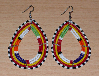 Boucles d'oreilles africaines de tradition tribale Massai composées de perles de rocaille multicolores glissées sur cinq rangées de fils de fer montés en forme de gouttes. Elles mesurent 8.3 cm de long et 4.5 cm de large, et se portent sur des oreilles percées.