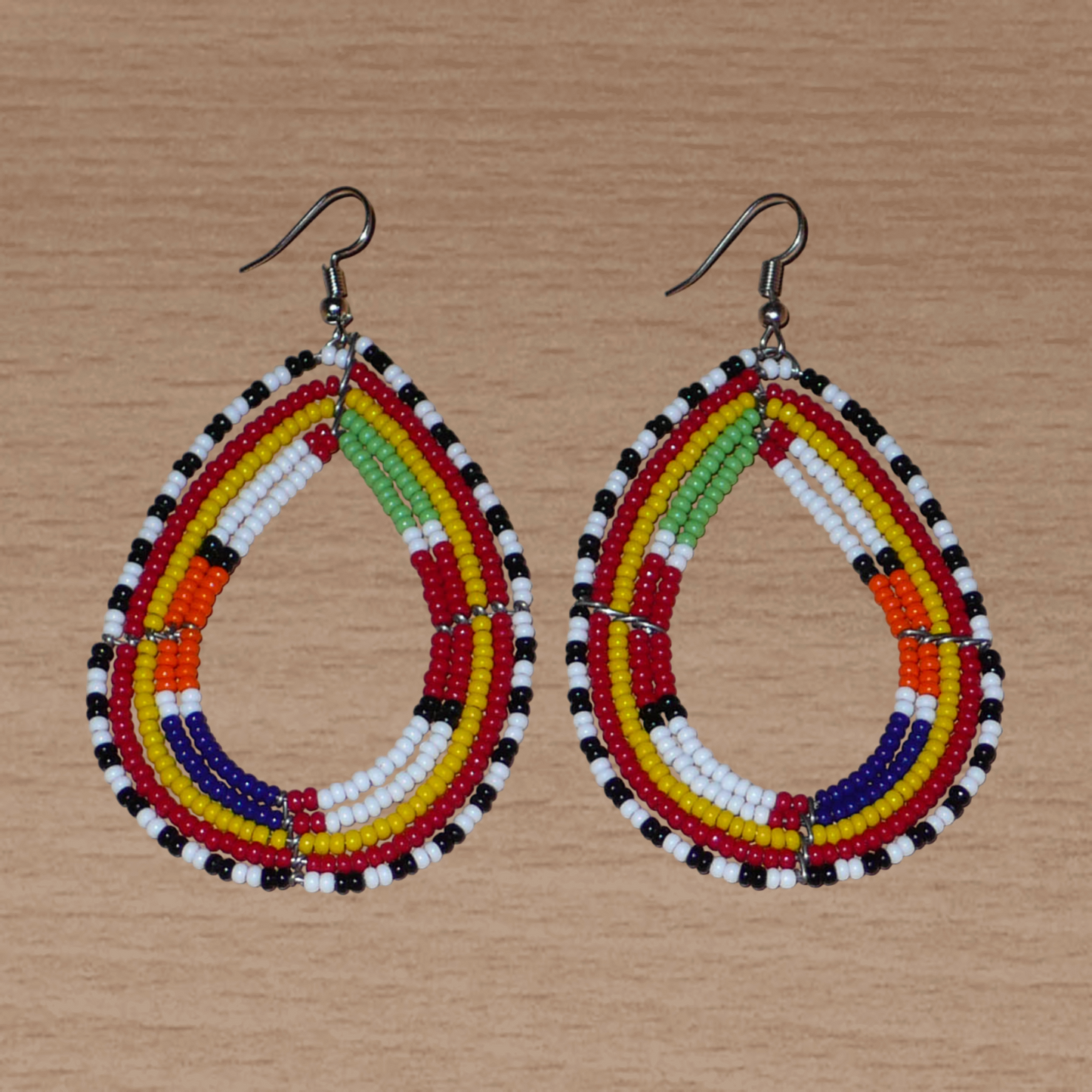 Boucles d'oreilles africaines de tradition tribale Massai composées de perles de rocaille multicolores glissées sur cinq rangées de fils de fer montés en forme de gouttes. Elles mesurent 8.3 cm de long et 4.5 cm de large, et se portent sur des oreilles percées.