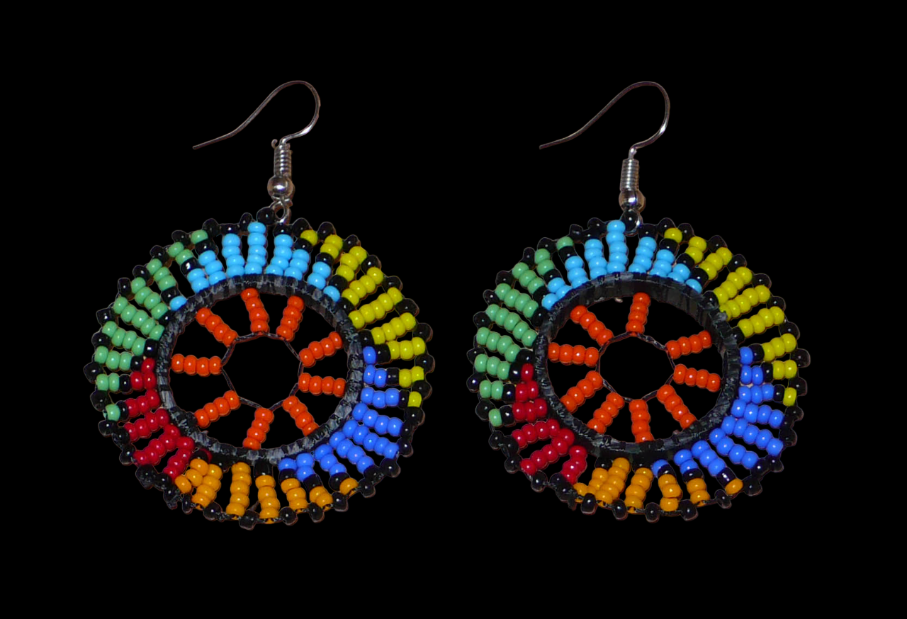 Boucles d'oreilles africaines rondes à motifs ethniques zoulous composées de perles de rocaille orange et multicolores glissées sur des fils de nylon fixés sur des structures circulaires en plastique. Elles mesurent 6 cm de long et 4 cm de large et se portent sur des oreilles percées. Timeless Fineries
