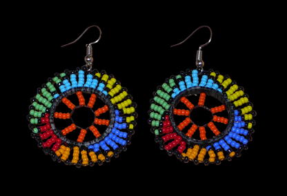 Boucles d'oreilles africaines rondes à motifs ethniques zoulous composées de perles de rocaille orange et multicolores glissées sur des fils de nylon fixés sur des structures circulaires en plastique. Elles mesurent 6 cm de long et 4 cm de large et se portent sur des oreilles percées. Timeless Fineries
