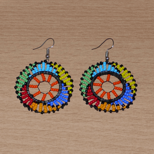 Boucles d'oreilles africaines rondes à motifs ethniques zoulous composées de perles de rocaille orange et multicolores glissées sur des fils de nylon fixés sur des structures circulaires en plastique. Elles mesurent 6 cm de long et 4 cm de large et se portent sur des oreilles percées.