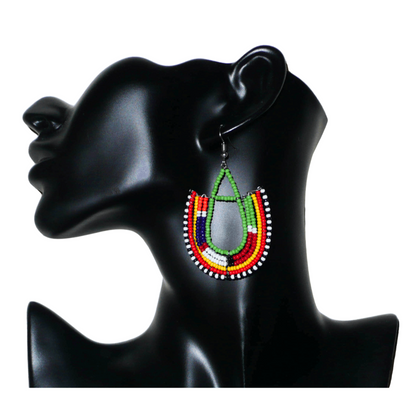 Cette paire de boucles d'oreilles africaines traditionnelles Massai riches en couleurs, de conception artisanale kenyane, apportera une touche tribale à votre look ! Elles se composent de perles de rocaille vertes et multicolores glissées sur des structures géométriques en fils de fer montés en forme d'ancres. Ces boucles d'oreilles mesurent 7.5 cm de long et 4.5 cm de large, et se portent avec des crochets en acier inoxydable sur des oreilles percées.