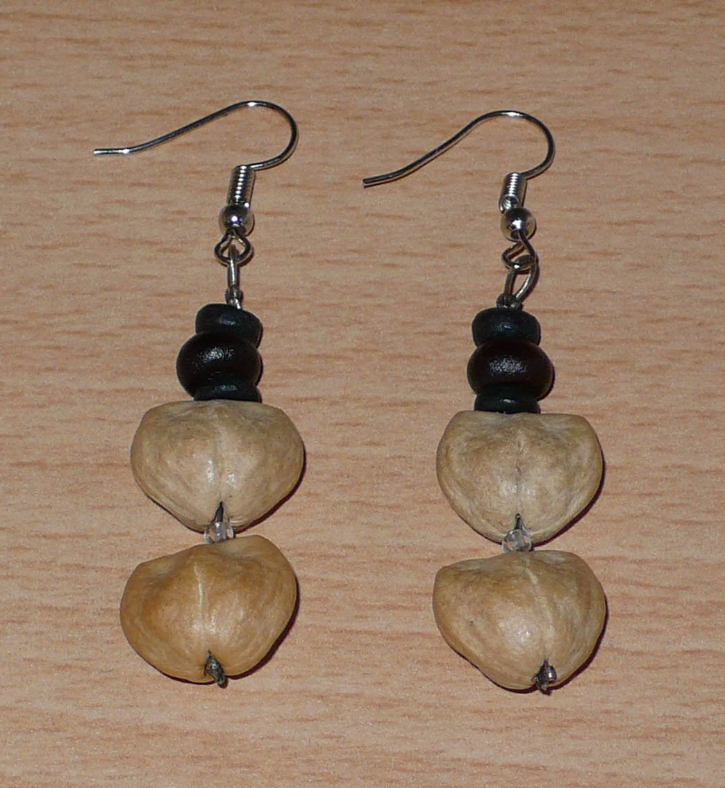 Boucles d'oreilles afro-caribéennes composées de perles de noix de coco et de graines organiques. De taille moyenne, ces boucles d'oreilles aux accents résolument exotiques mesurent 6 cm de long et 1,5 cm de large ; elles se portent avec des crochets en acier inoxydable sur des oreilles percées.