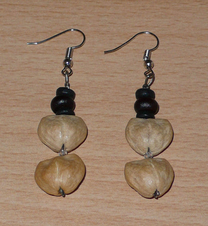 Boucles d'oreilles afro-caribéennes composées de perles de noix de coco et de graines organiques. De taille moyenne, ces boucles d'oreilles aux accents résolument exotiques mesurent 6 cm de long et 1,5 cm de large ; elles se portent avec des crochets en acier inoxydable sur des oreilles percées.