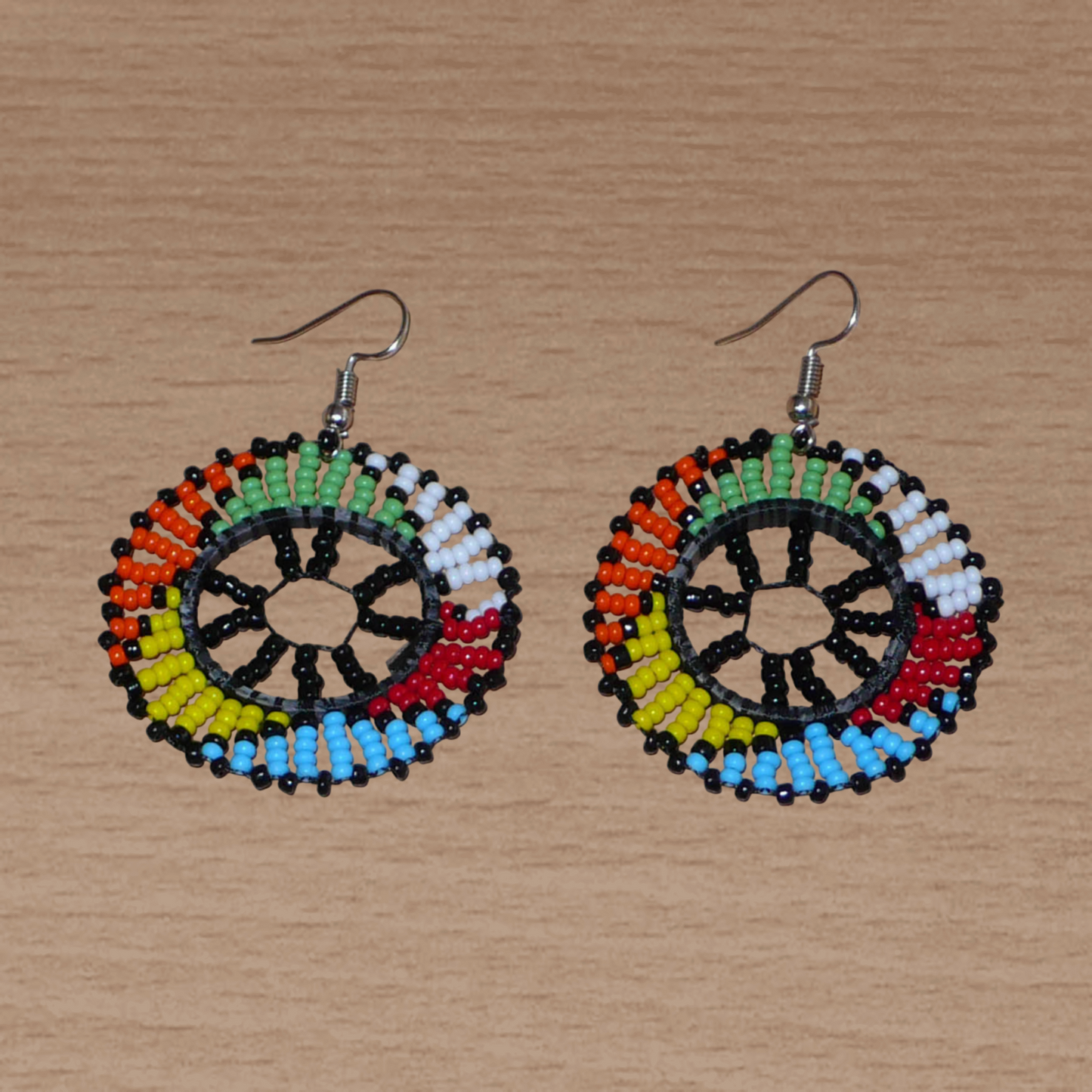 Boucles d'oreilles ethniques rondes à motifs zoulous composées de perles de rocaille noires et multicolores. De taille moyenne et légères à porter, elles mesurent 6 cm de long et 4 cm de large. 