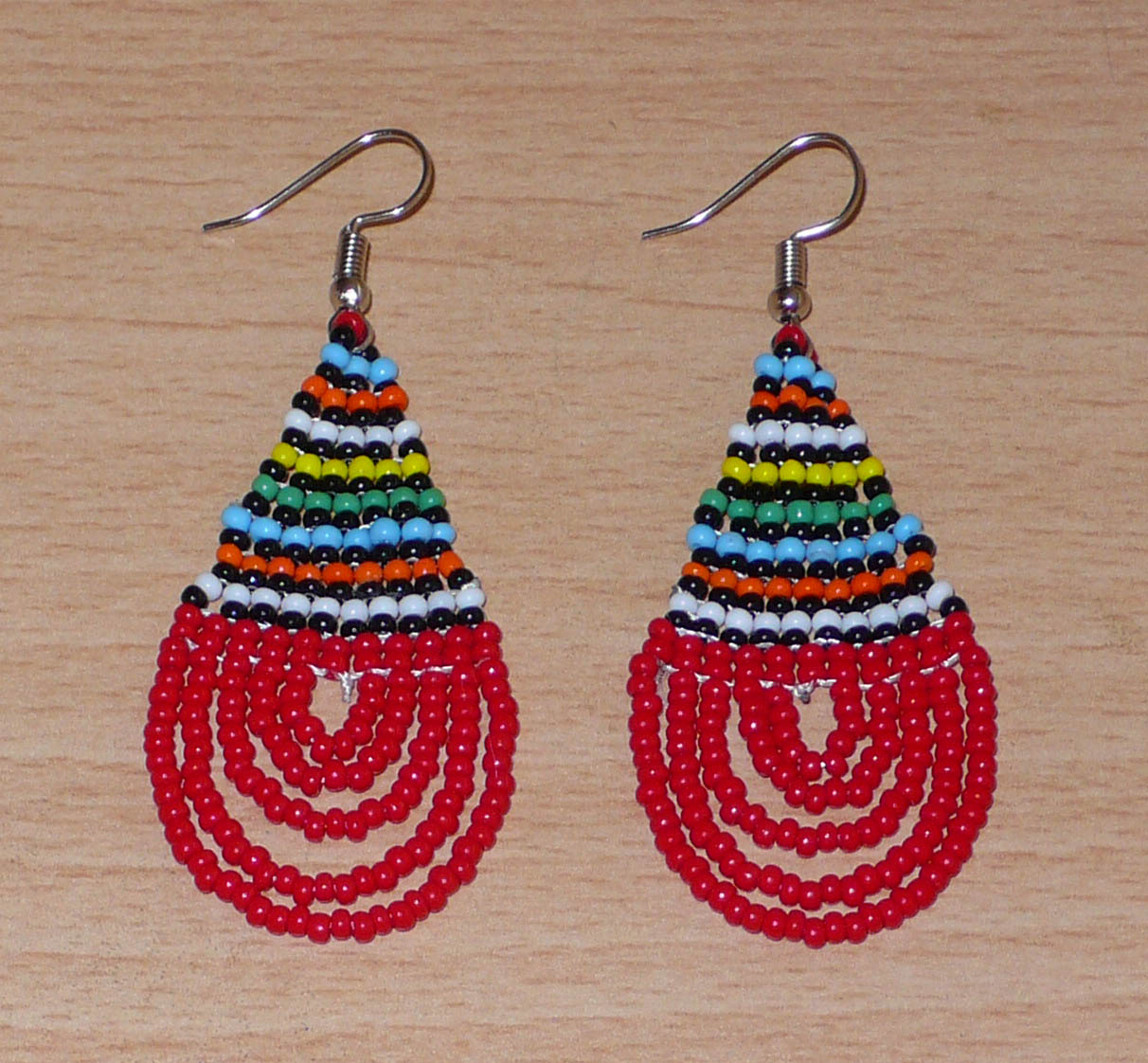 Boucles d'oreilles sud-africaines rouges et multicolores composées de perles de rocaille tissées en forme de gouttes. Elles mesurent 7 cm de long et 2,5 cm de large et se portent sur des oreilles percées.