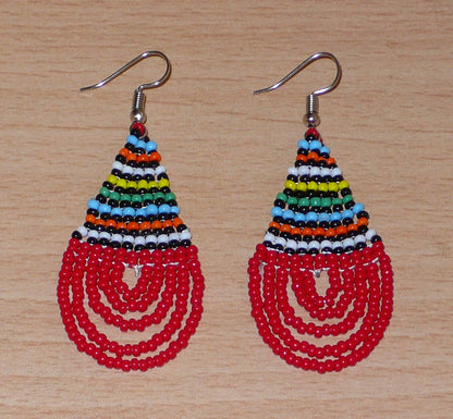 Boucles d'oreilles sud-africaines rouges et multicolores composées de perles de rocaille tissées en forme de gouttes. Elles mesurent 7 cm de long et 2,5 cm de large et se portent sur des oreilles percées.
