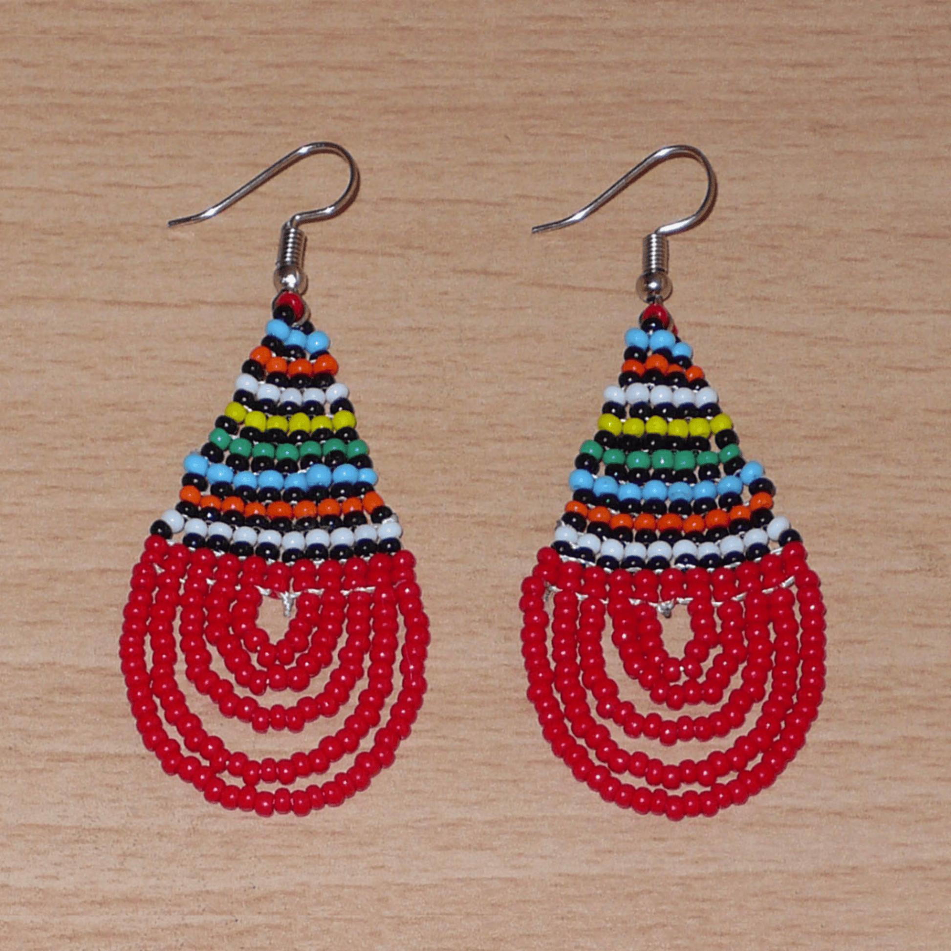 Boucles d'oreilles sud-africaines rouges et multicolores composées de perles de rocaille tissées en forme de gouttes. Elles mesurent 7 cm de long et 2,5 cm de large et se portent sur des oreilles percées.