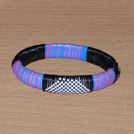 Bracelet africain fabriqué dans une démarche eco-responsable avec des matériaux de récupération : il se compose de motifs ethniques tissés à partir de fines bandes de plastique recyclé noir, blanc, rose et bleu.