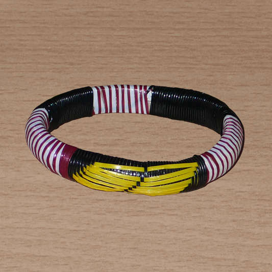 Bracelet africain fabriqué dans une approche eco-responsable à partir de matériaux de récupération : il se compose de motifs ethniques tissés avec des bandes de plastique recyclé noir, jaune, bordeaux et blanc.