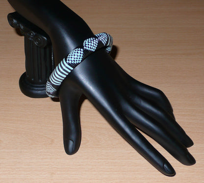 Bracelet africain noir et bleu à motifs ethniques rayés et à damiers, fabriqué au Burkina Faso dans une optique artisanale eco-responsable, composé de fines bandes de plastique recyclé.