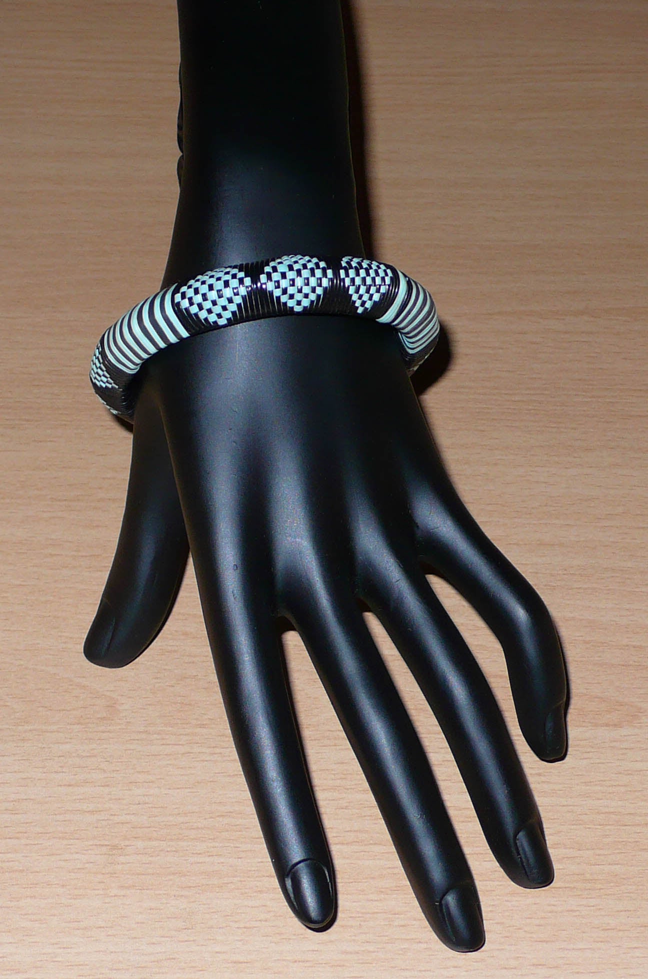 Bracelet africain noir et bleu à motifs ethniques rayés et à damiers, fabriqué au Burkina Faso dans une optique artisanale eco-responsable, composé de fines bandes de plastique recyclé.