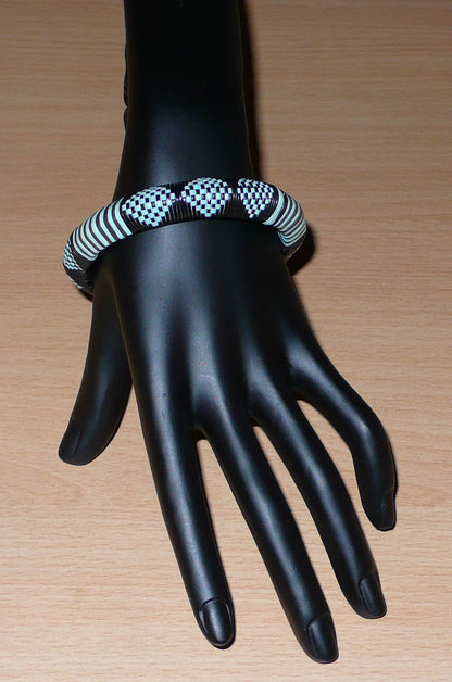 Bracelet africain noir et bleu à motifs ethniques rayés et à damiers, fabriqué au Burkina Faso dans une optique artisanale eco-responsable, composé de fines bandes de plastique recyclé.