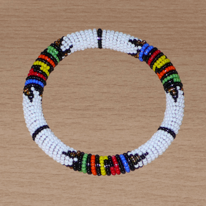 Bracelet africain tubulaire à motifs traditionnels zoulous composé de perles de rocaille blanches et multicolores ; glissées sur du fil de nylon, les perles sont ensuite enroulées autour d'un tube en plastique. Ce bracelet a une circonférence de 21 cm, un diamètre de 6.5 cm, et une épaisseur de 1 cm.