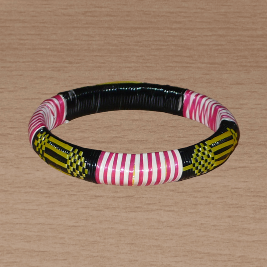Bracelet africain fabriqué dans une optique eco-responsable avec des matériaux de récupération : il se compose de motifs ethniques tissés à partir de fines bandes de plastique recyclé noir, jaune, rouge et blanc.
