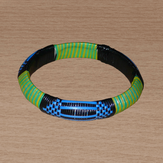 Bracelet africain malien à motifs ethniques : fabriqué dans une démarche eco-responsable, il est tressé avec de fines bandes de plastique recyclé noir, bleu, vert et jaune. La circonférence interne de ce bracelet est de 21 cm, avec un diamètre interne de 6.8 cm et une épaisseur de 1.3 cm.
