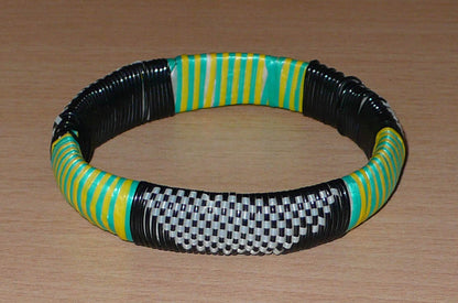 Bracelet africain eco-friendly tressé avec des fines bandes de plastique recyclé noir, blanc, vert et jaune.