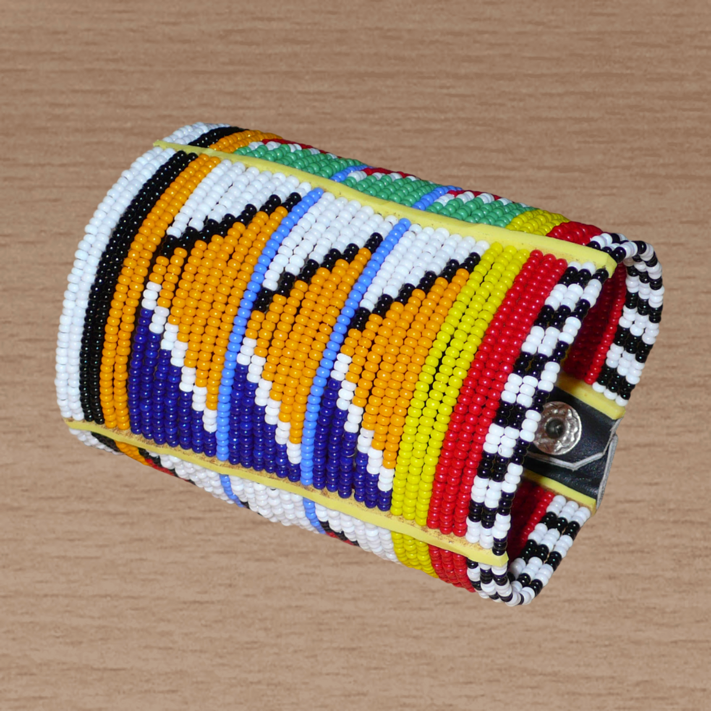 Bracelet africain traditionnel à motifs tribaux Massai composé de perles de rocaille multicolores glissées sur trente-six rangées de fils de fer insérés dans des charnières en plastique, il s'attache avec des boutons pressions.