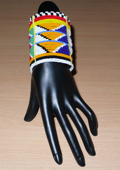 Bracelet africain traditionnel à motifs tribaux Massai composé de perles de rocaille multicolores glissées sur trente-six rangées de fils de fer insérés dans des charnières en plastique, il s'attache avec des boutons pressions.