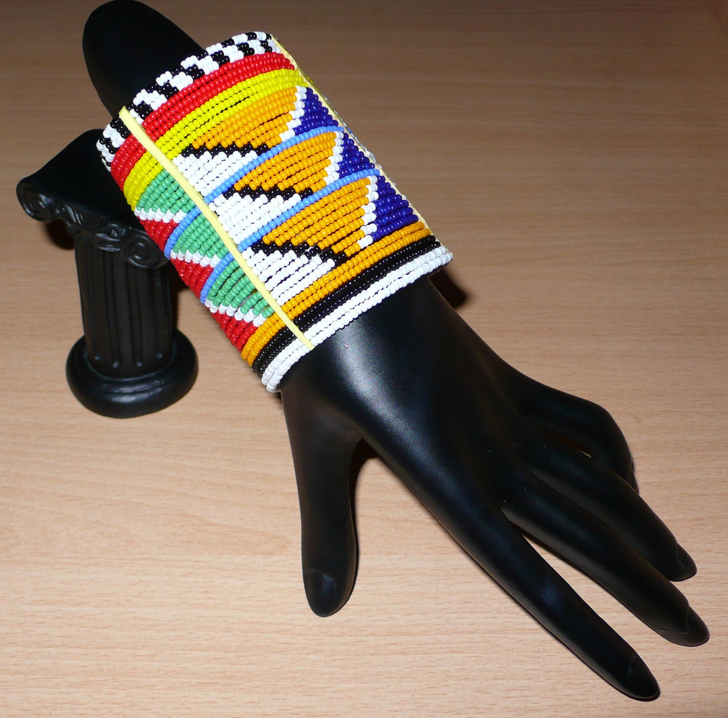 Bracelet africain traditionnel à motifs tribaux Massai composé de perles de rocaille multicolores glissées sur trente-six rangées de fils de fer insérés dans des charnières en plastique, il s'attache avec des boutons pressions.