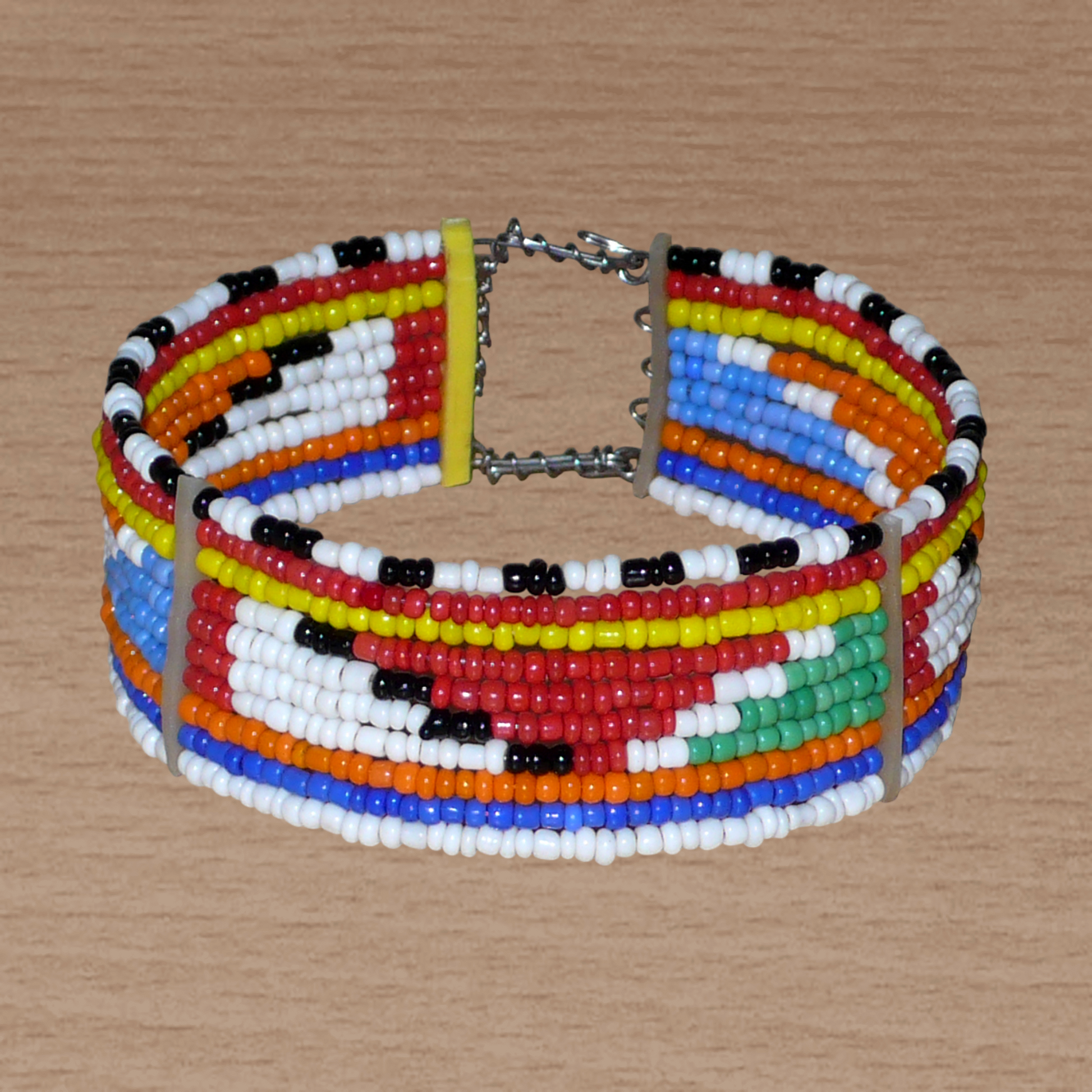 Bracelet africain Massai à motifs tribaux composé de perles de rocaille multicolores glissées sur 10 rangées de fer insérés dans des charnières en plastique recyclé.