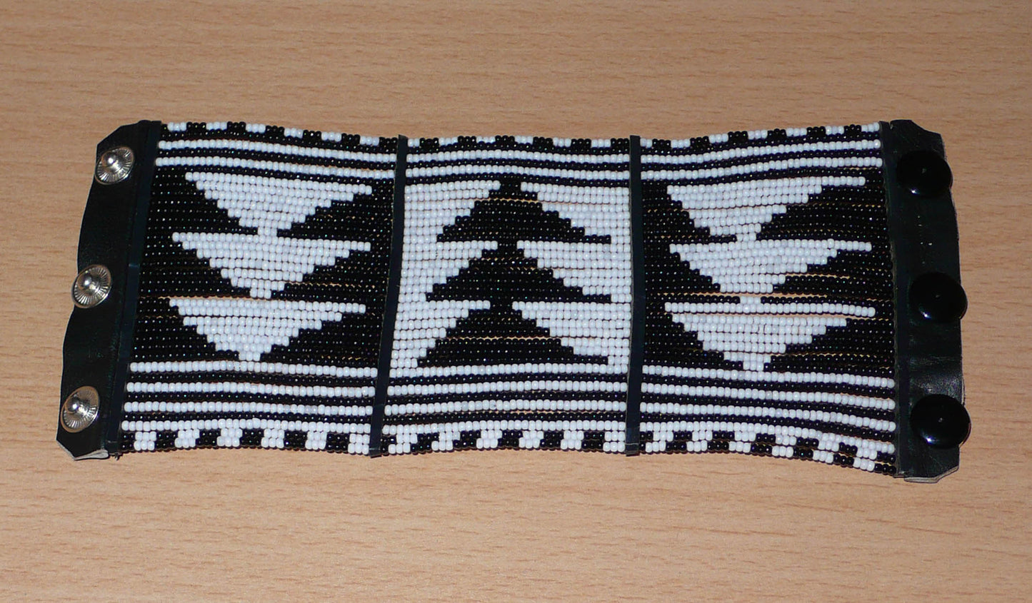 Bracelet africain Massai bicolore à motifs ethniques composé de plusieurs rangées de perles de rocaille noires et blanches.