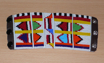 Bracelet africain pour enfant à motifs ethniques traditionnels Massai composé de trente-six rangées de perles de rocaille blanches et multicolores glissées sur des fils de fer fixés sur des charnières en plastique blanc.