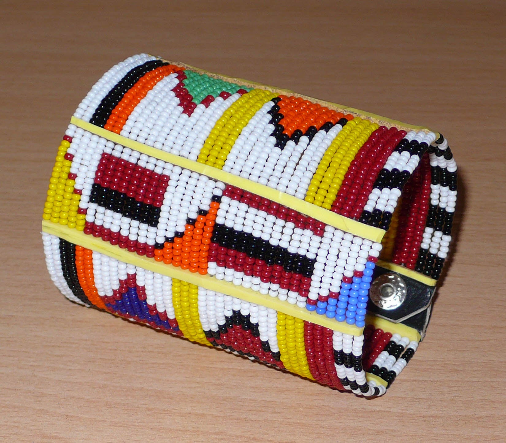 Bracelet africain traditionnel à motifs ethniques Massai composé de perles de rocaille blanches et multicolores fixées sur trente-six rangées de fils de fer.