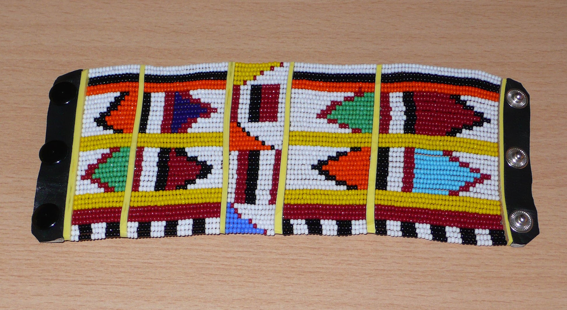 Bracelet africain traditionnel à motifs ethniques Massai composé de perles de rocaille blanches et multicolores fixées sur trente-six rangées de fils de fer.