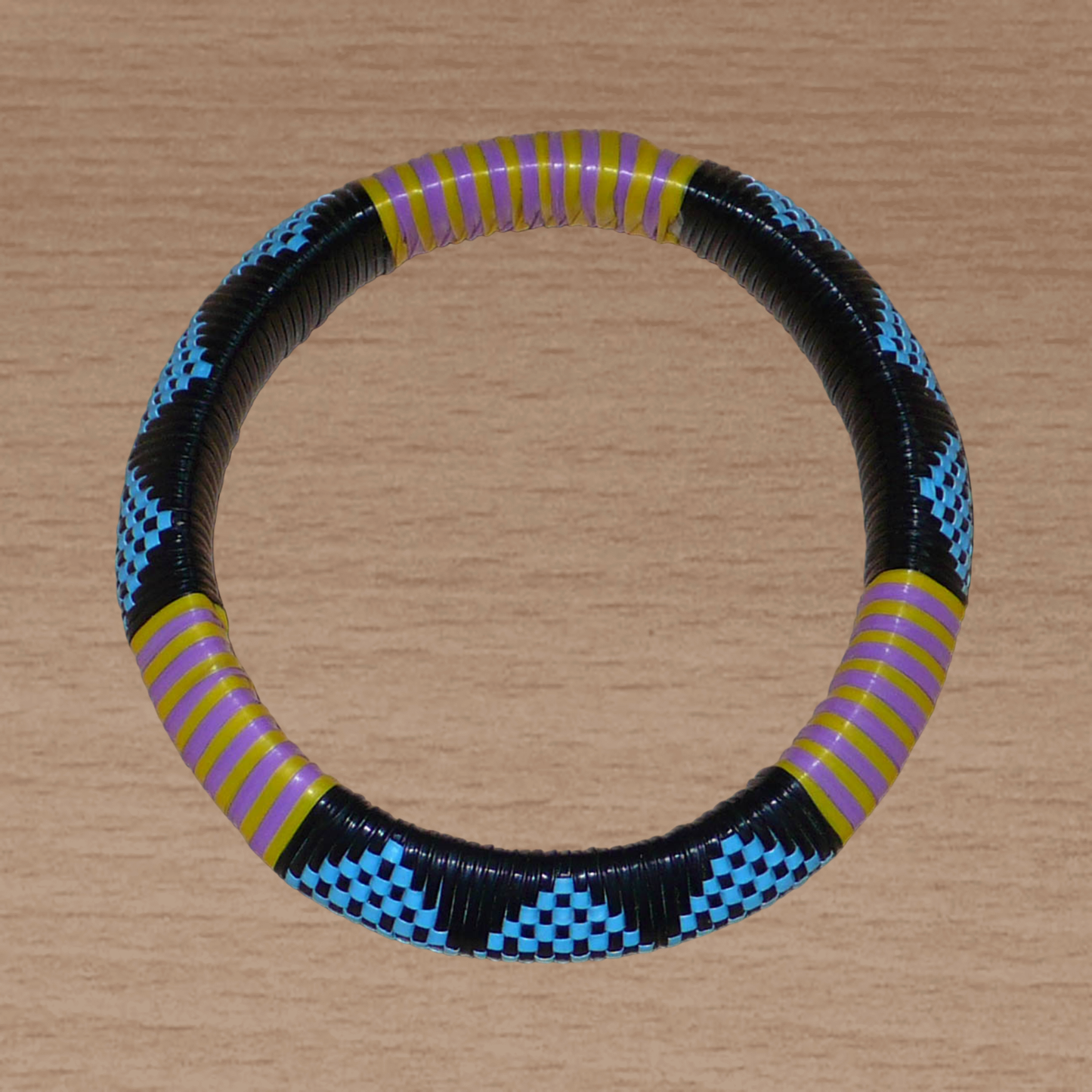 Bracelet africain à motifs tribaux composé de plastique recyclé bleu, noir, violet et jaune.