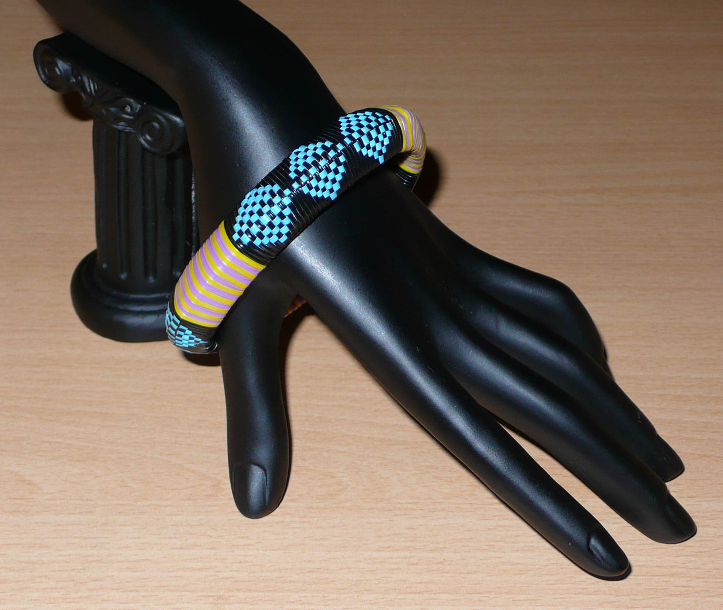 Bracelet africain à motifs tribaux composé de plastique recyclé bleu, noir, violet et jaune.