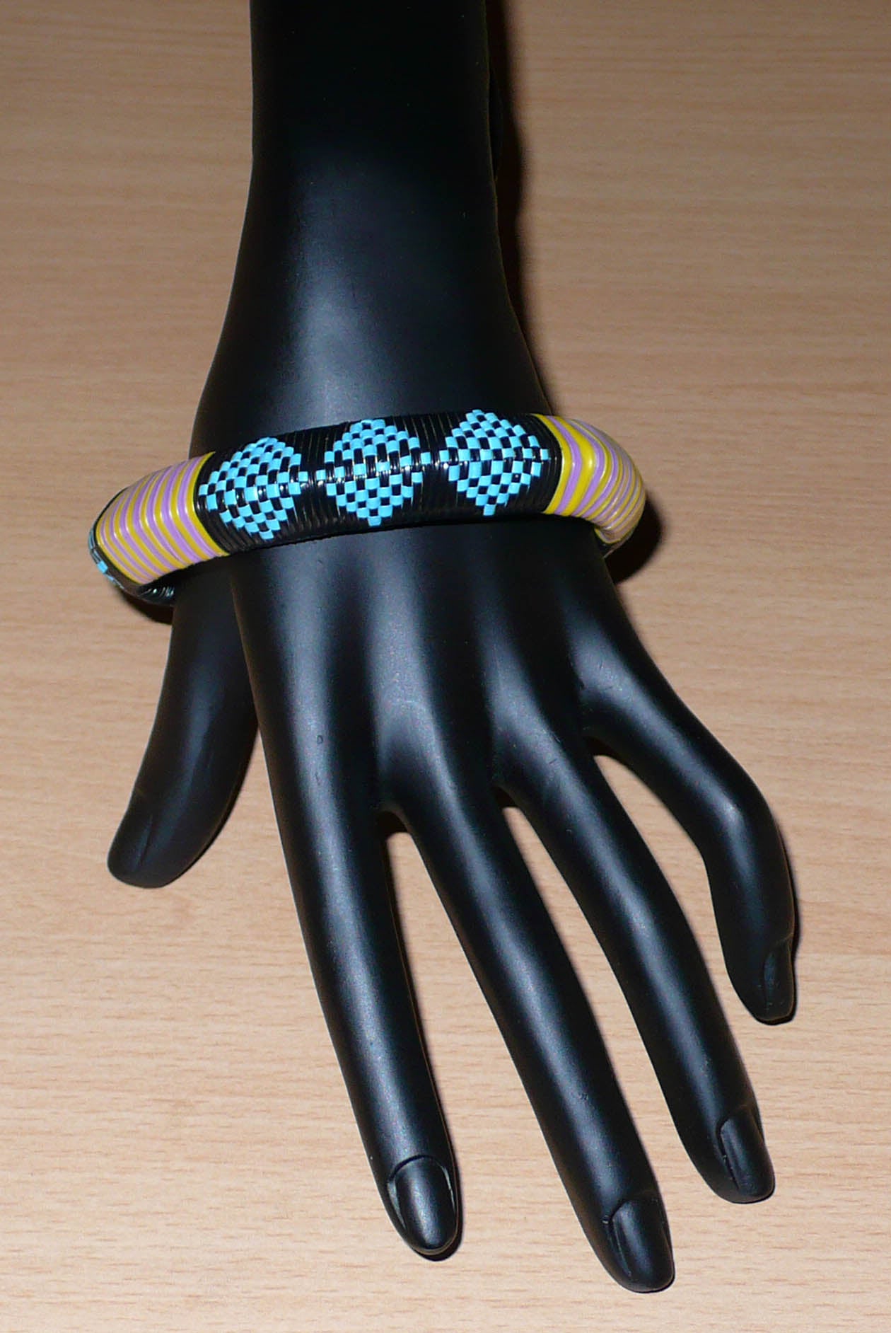 Bracelet africain à motifs tribaux composé de plastique recyclé bleu, noir, violet et jaune.