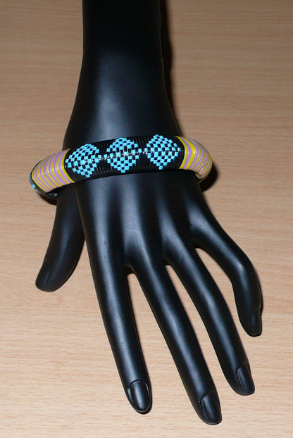 Bracelet africain à motifs tribaux composé de plastique recyclé bleu, noir, violet et jaune.