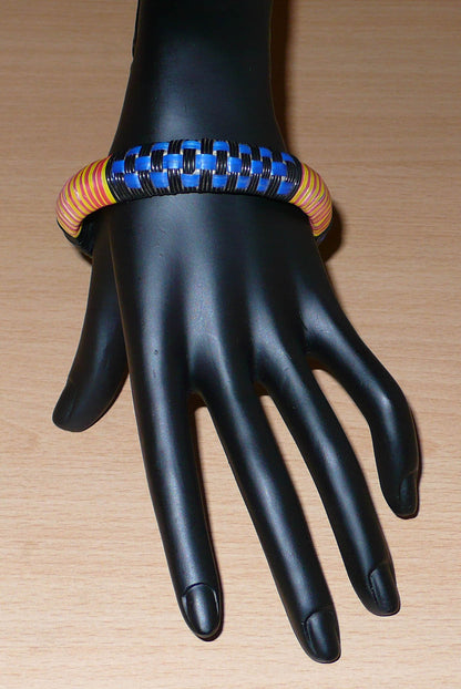 Fabriqué dans une démarche eco-friendly, ce bracelet africain arbore des motifs ethniques tissés avec du plastique recyclé noir, bleu, jaune et rose.