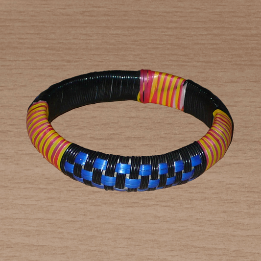 Fabriqué au Mali dans une approche eco-friendly, ce bracelet africain à motifs ethniques à damiers se compose d'un tissage de fines bandes de plastique recyclé noir, bleu, jaune et rose.
