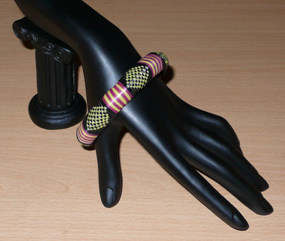 Bracelet africain tricolore à motifs tribaux : fabriqué au Burkina Faso dans une optique artisanale eco-responsable, il se compose de plastique recyclé jaune, noir et violet.
