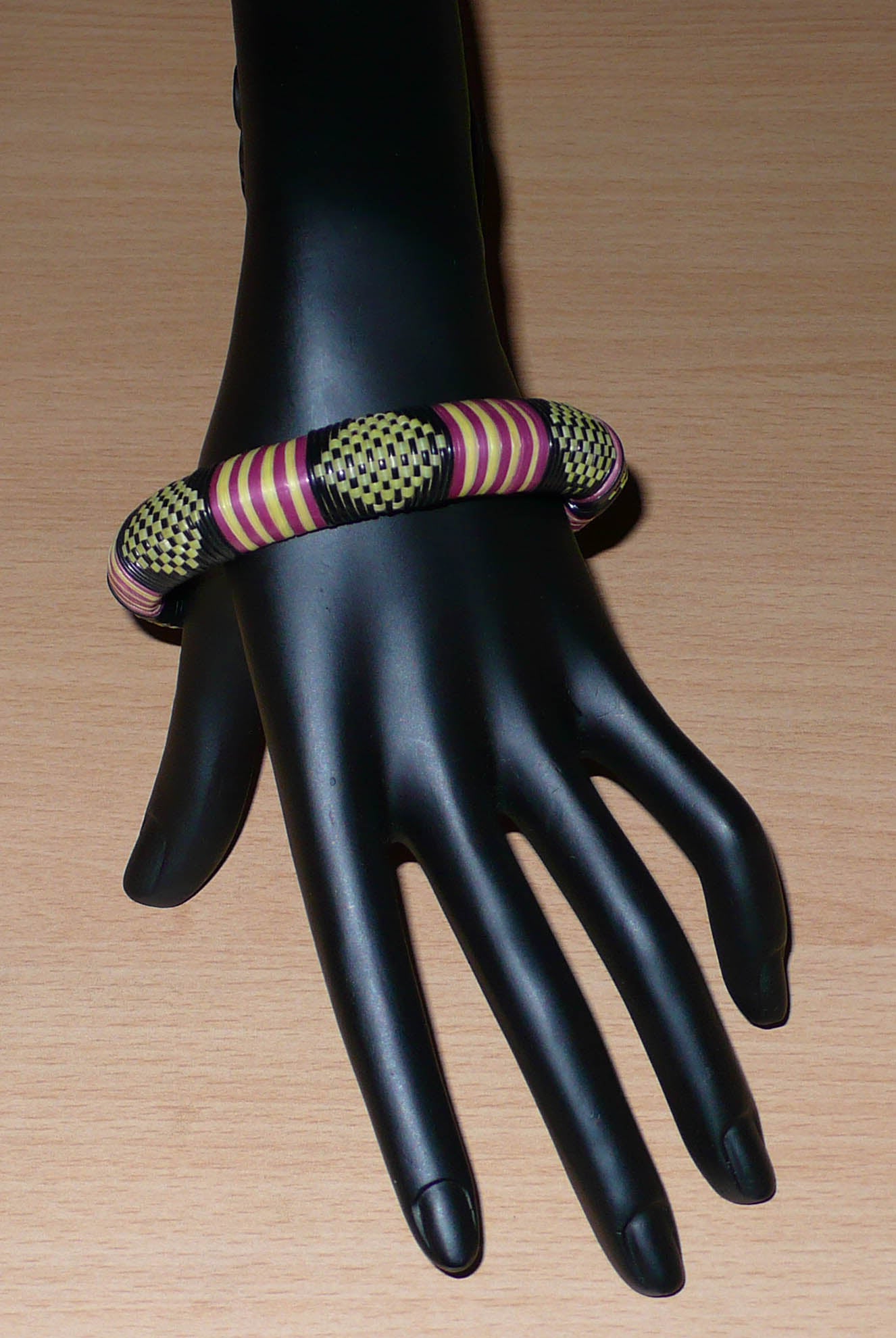 Bracelet africain tricolore à motifs tribaux : fabriqué au Burkina Faso dans une optique artisanale eco-responsable, il se compose de plastique recyclé jaune, noir et violet.