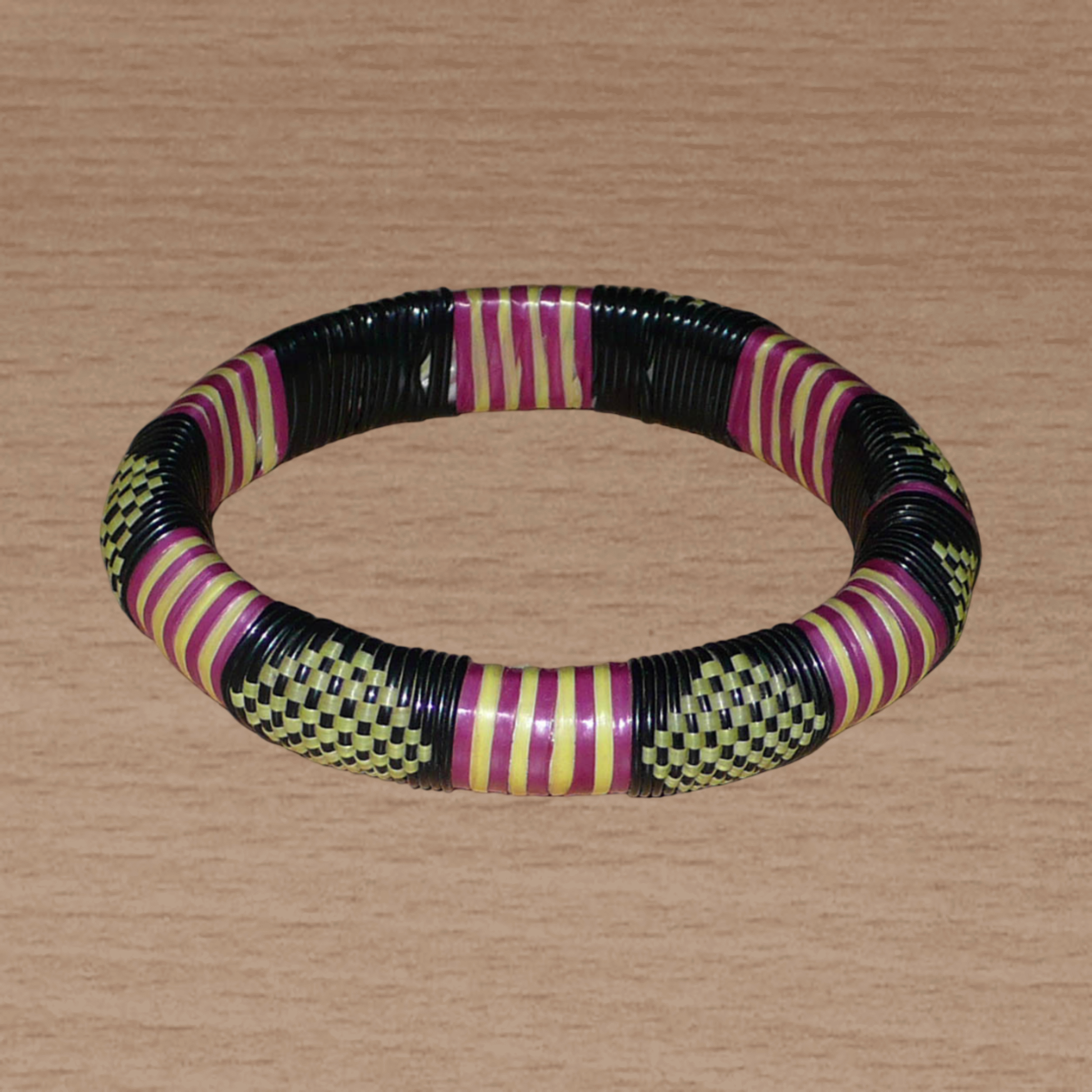 Bracelet africain tricolore à motifs tribaux : fabriqué au Burkina Faso dans une optique artisanale eco-responsable, il se compose de plastique recyclé jaune, noir et violet.
