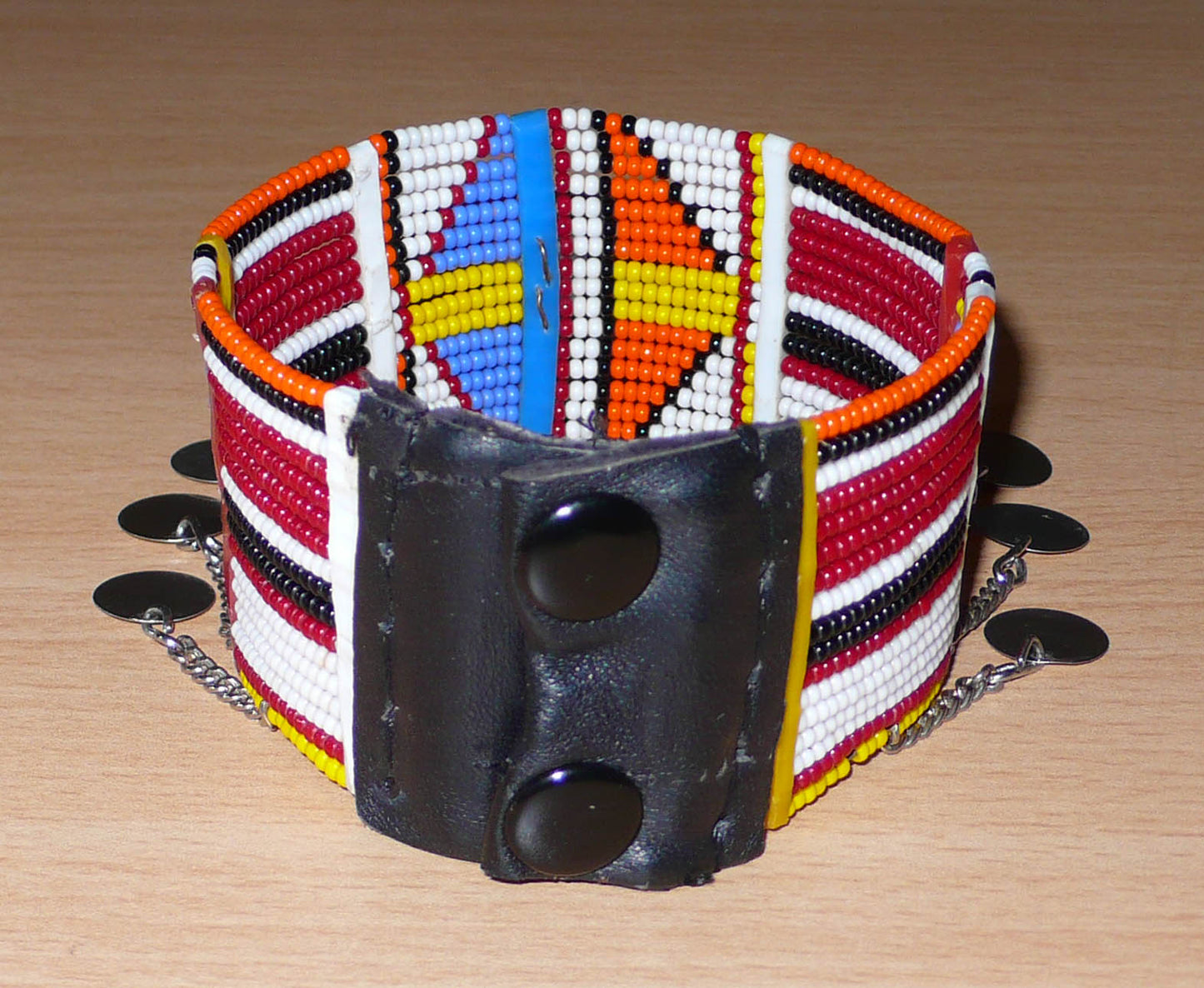 Bracelet de cheville africain Massai à motifs géométriques traditionnel composé de dix-sept rangées de perles de rocaille multicolores et prolongé de chaînettes ornées de disques de métal.