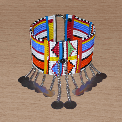 Authentique bracelet africain de cheville à motifs tribaux Massai composé de dix-huit rangées de perles de rocaille, et décoré de chaînettes ornées de disques métalliques.