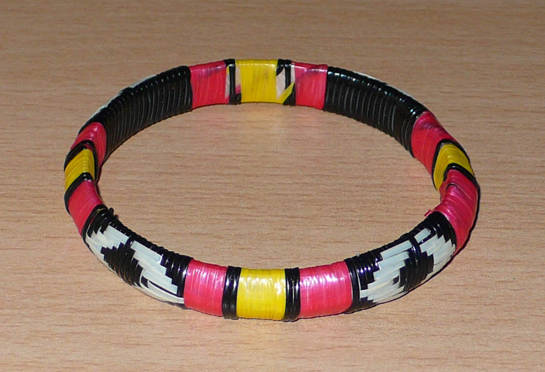 Fabriqué dans une approche eco-friendly, ce bracelet malien à motifs ethniques est tissé avec de fines bandes de plastique recyclé noir, jaune, rouge et blanc.