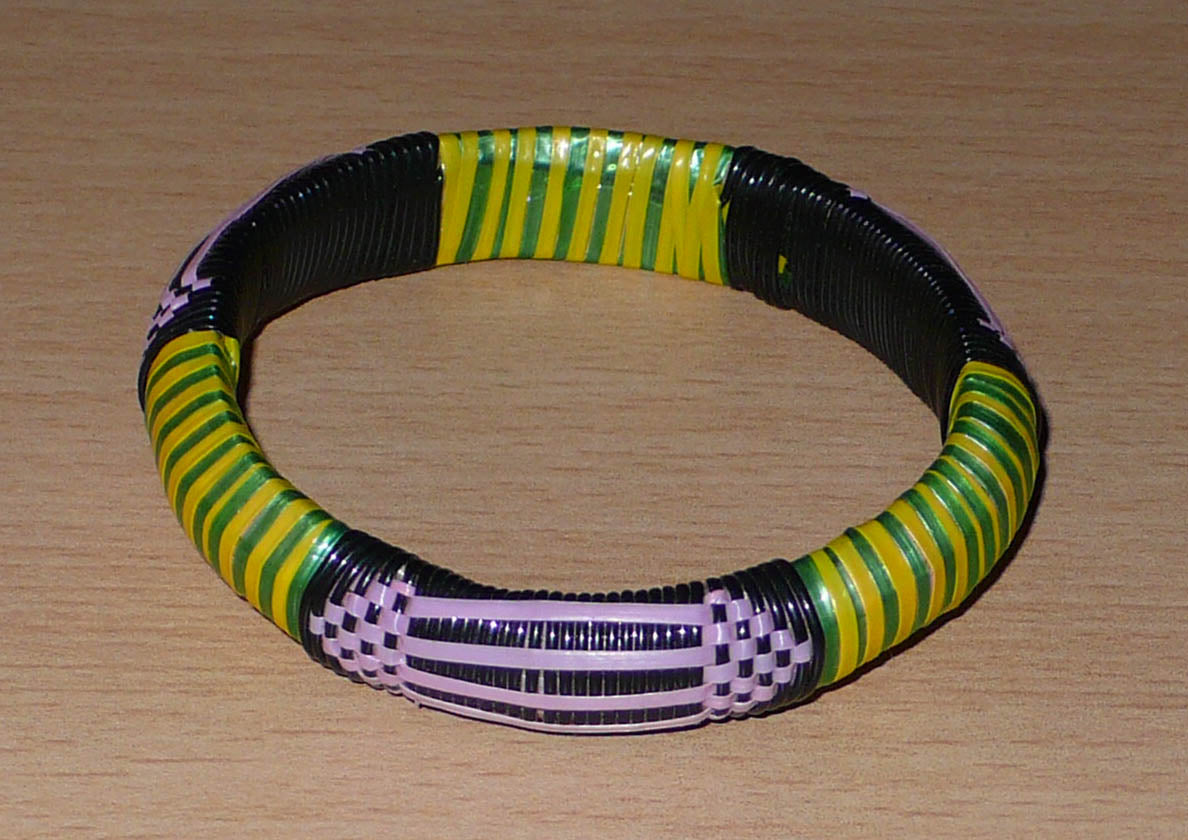 Bracelet africain écolo à motifs ethniques tissés avec des bandes de plastique recyclé noir, violet, vert et jaune.