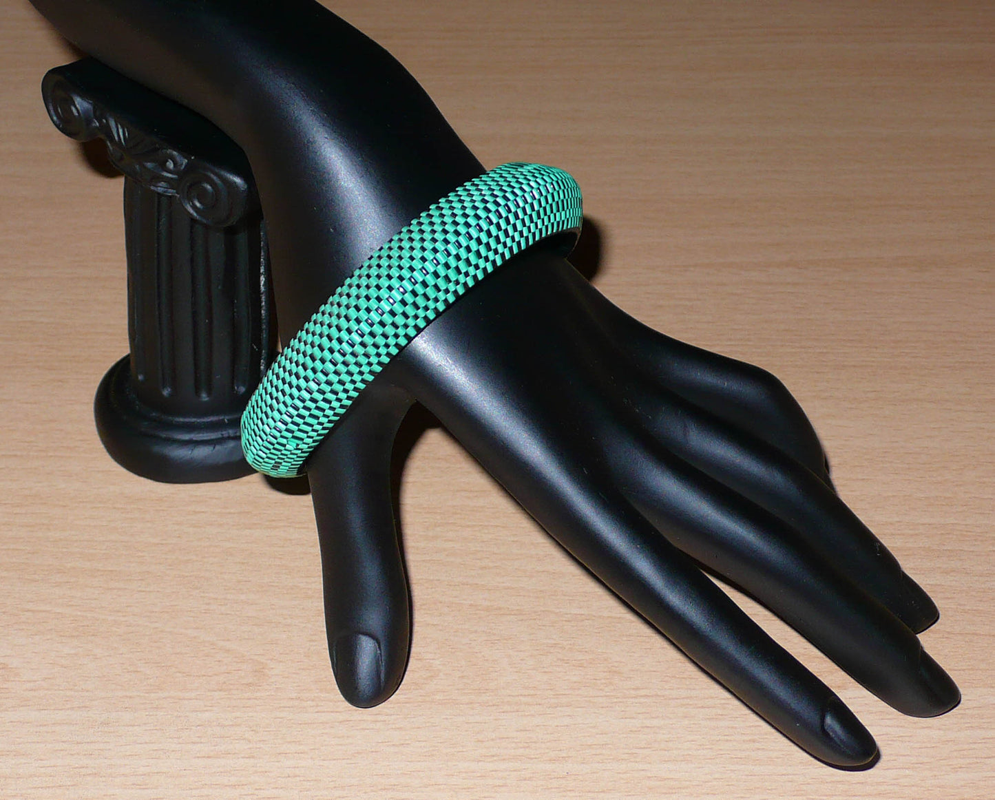 Bracelet africain épais à petits damiers tissés à partir de très fines bandes de plastique recyclé vert et noir.  Ce bracelet a une circonférence interne de 21,5 cm, un diamètre de 6,5 cm et une épaisseur de 1,5 cm.