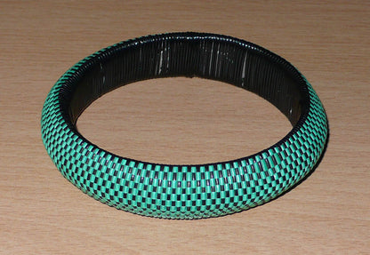 Bracelet africain épais à petits damiers tissés à partir de très fines bandes de plastique recyclé vert et noir.  Ce bracelet a une circonférence interne de 21,5 cm, un diamètre de 6,5 cm et une épaisseur de 1,5 cm.