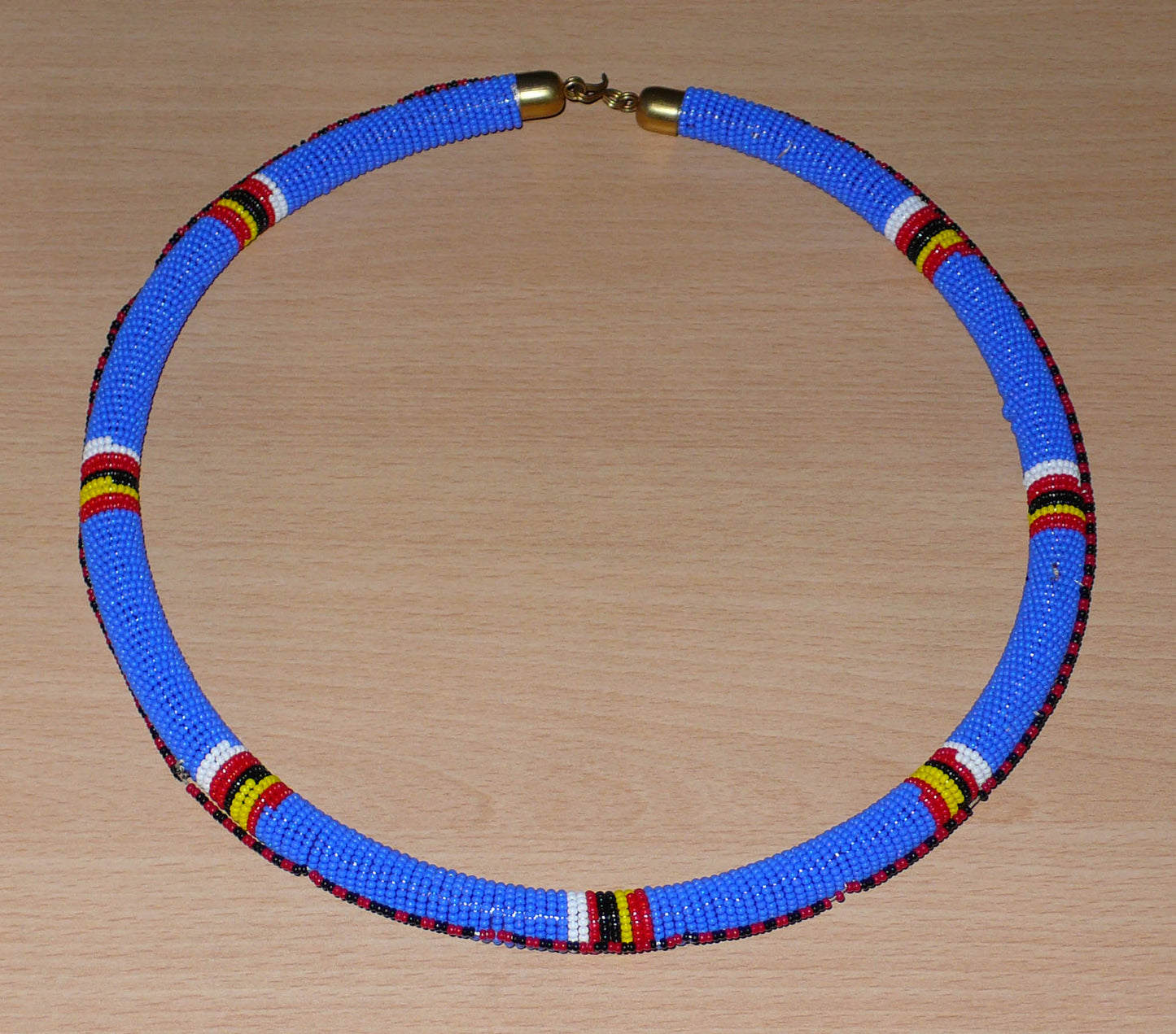 Collier africain Massai tubulaire composé de perles de rocaille principalement bleues, décoré de motifs ethniques perlés.