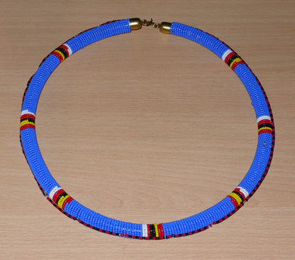 Collier africain Massai tubulaire composé de perles de rocaille principalement bleues, décoré de motifs ethniques perlés.
