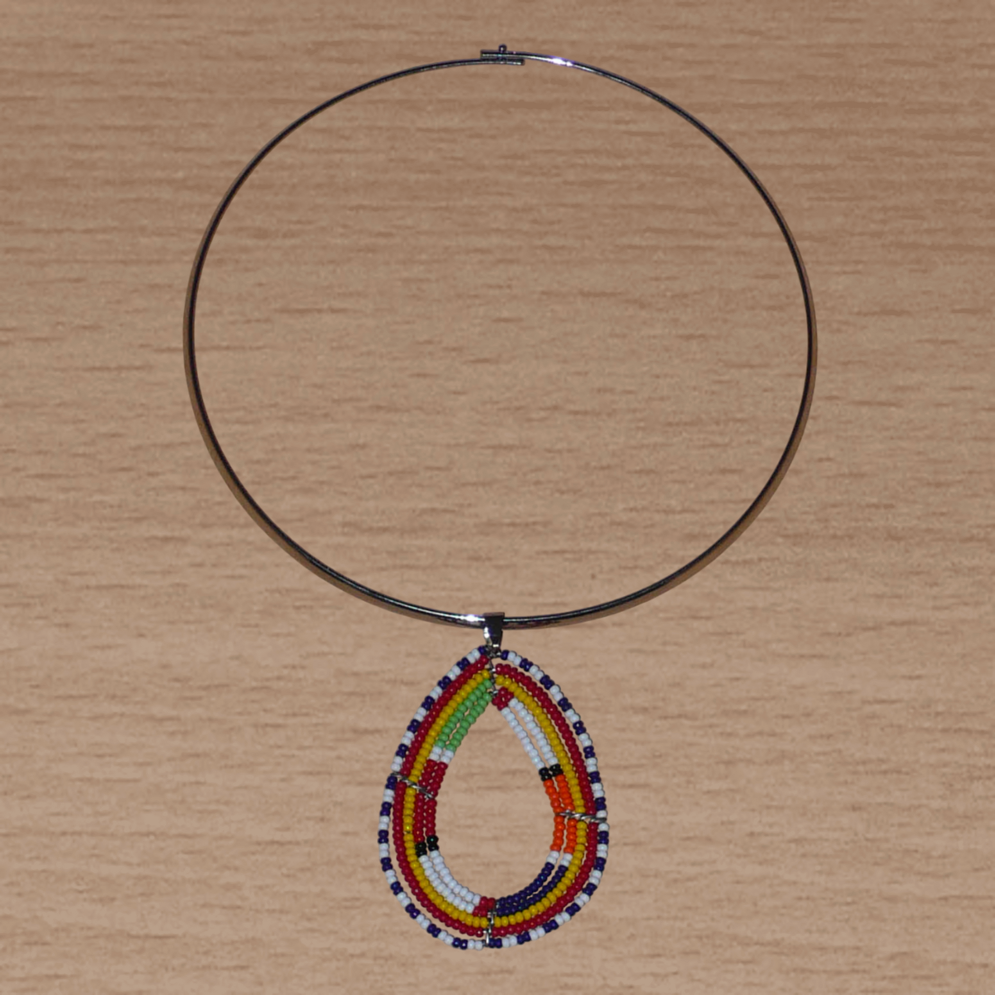 Bijou africain composé d'un collier ras de cou en laiton agrémenté d'un pendentif ethnique Massai en forme de goutte fait de perles de rocaille multicolores.