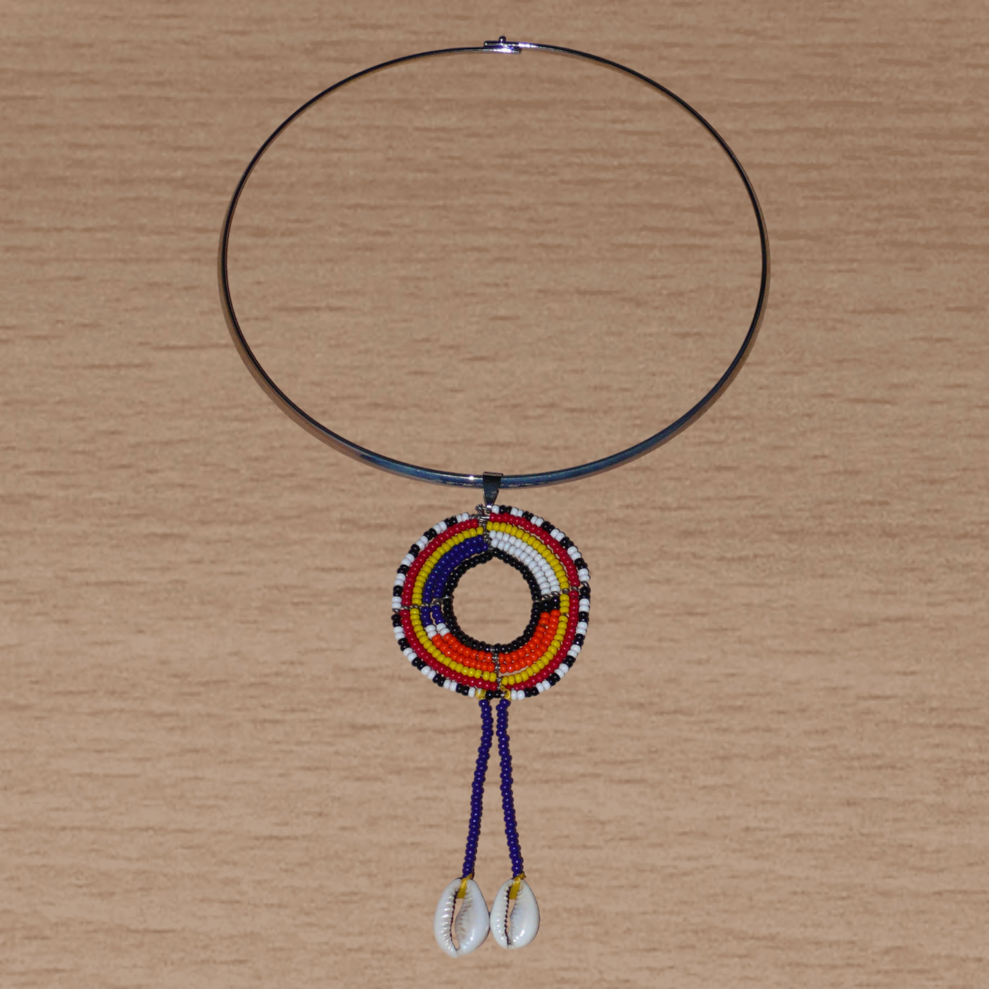 Collier africain Massai composé d'un ras de cou en laiton agrémenté d'un long pendentif ethnique fait de perles de rocaille et de coquillages cauris.