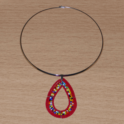 Collier ethnique de style afro bohème composé d'un ras de cou en laiton orné d'un pendentif en forme de goutte fait de perles de rocaille rouges et multicolores. Il mesure 20 cm de long, la circonférence du ras de cou en laiton est de 42,5 cm et son diamètre de 13,5 cm ; le pendentif perlé mesure 7 cm de long et 4,5 cm de large.