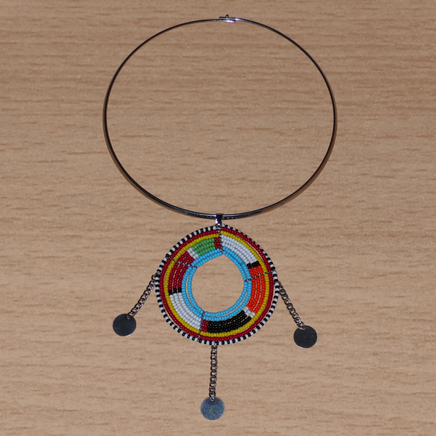 Collier africain de style tribal afro chic : il se compose d'un ras de cou en laiton rehaussé d'un long et large pendentif à motifs ethniques Massai fait de perles de rocaille multicolores et de chaînettes ornées de disques métalliques.